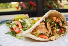 Grilled chicken pita sandwich with fresh vegetables, served with a side salad.