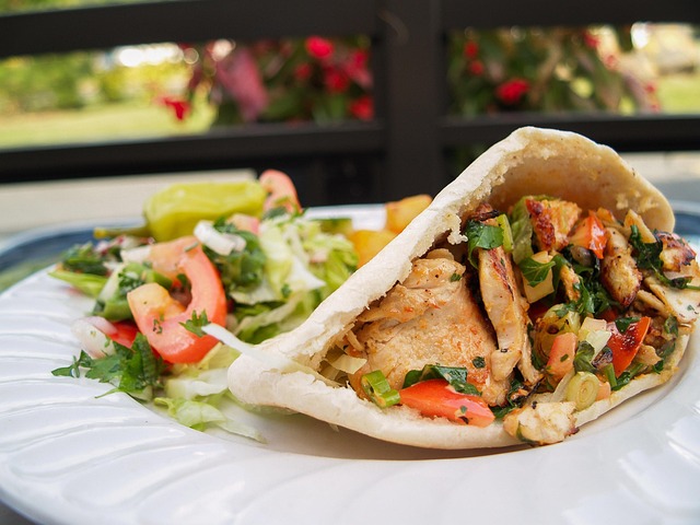 Grilled chicken pita sandwich with fresh vegetables, served with a side salad.