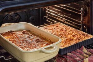 Two freshly baked casseroles in the oven, with a golden, cheesy crust on top.